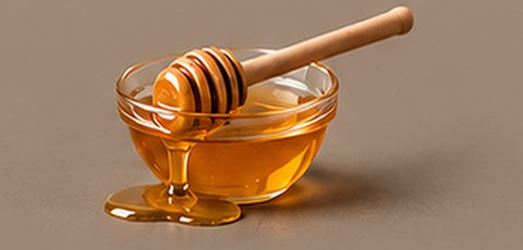 Bowl of honey with a wooden dipper